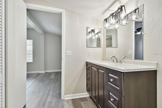 bathroom featuring a textured ceiling, ceiling fan, vaulted ceiling, vanity, and hardwood / wood-style flooring