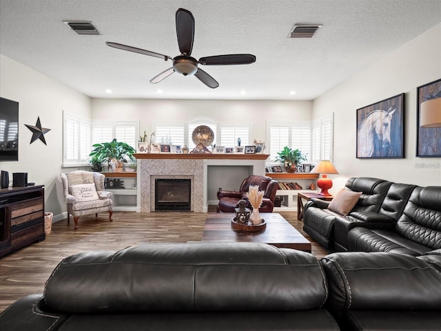 living room with wood-type flooring, ceiling fan, and a textured ceiling