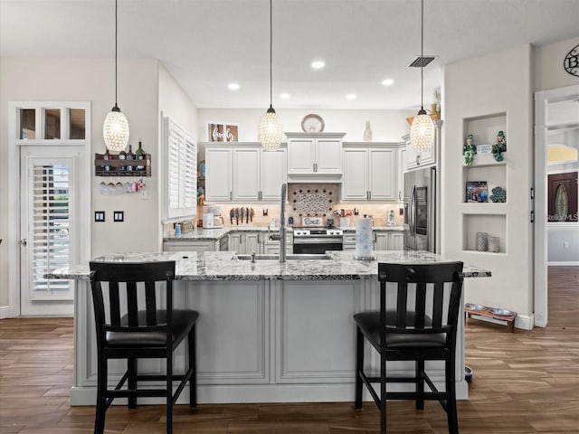 kitchen featuring a kitchen bar, decorative light fixtures, a spacious island, and appliances with stainless steel finishes