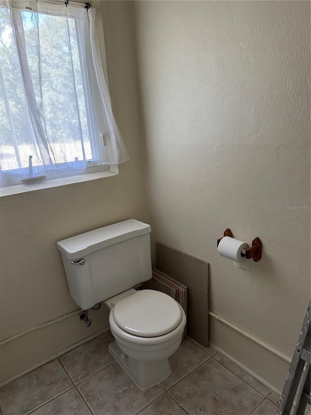 bathroom featuring toilet, plenty of natural light, and tile patterned flooring