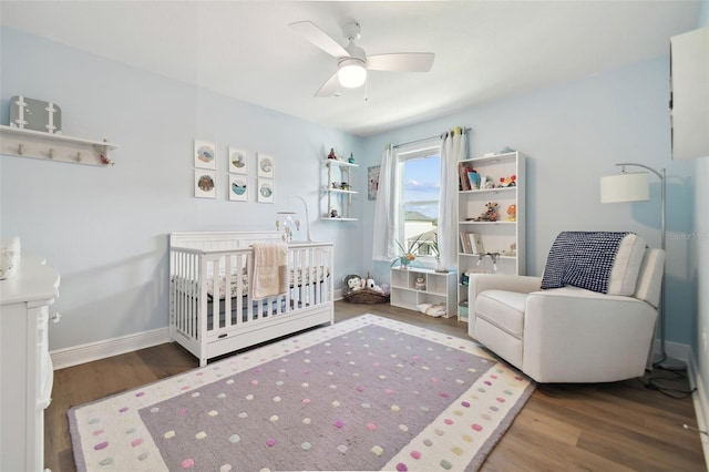 bedroom featuring ceiling fan, wood-type flooring, and a crib