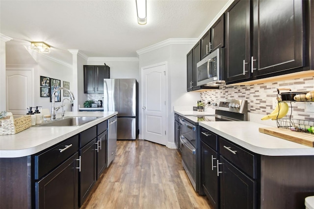 kitchen featuring stainless steel appliances, sink, decorative backsplash, and light wood-type flooring