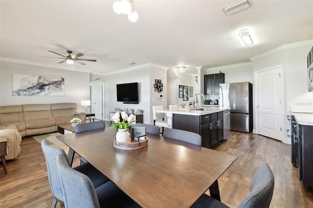 dining room featuring dark hardwood / wood-style flooring, sink, crown molding, and ceiling fan