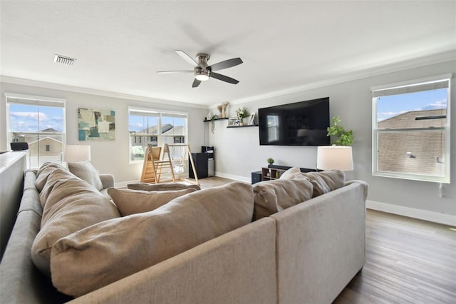 living room featuring wood-type flooring, a healthy amount of sunlight, ceiling fan, and crown molding