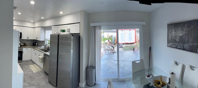 kitchen with stainless steel appliances, white cabinetry, sink, and tasteful backsplash