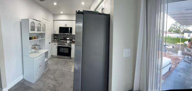 kitchen with white cabinetry, decorative backsplash, appliances with stainless steel finishes, and a barn door