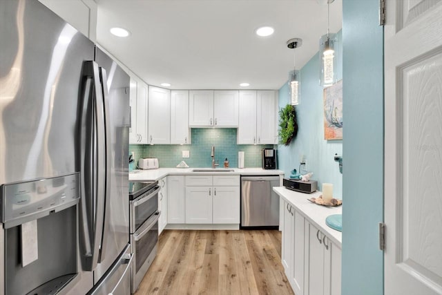 kitchen featuring appliances with stainless steel finishes, sink, light wood-type flooring, and white cabinets