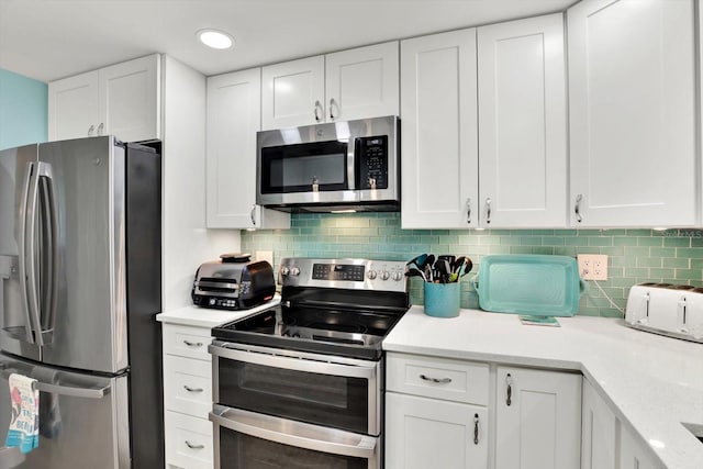 kitchen with decorative backsplash, white cabinets, stainless steel appliances, and light stone counters