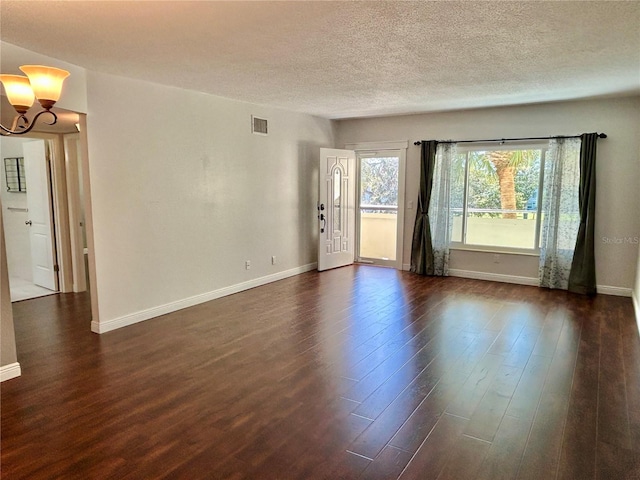 unfurnished room featuring a notable chandelier, a textured ceiling, and dark hardwood / wood-style floors