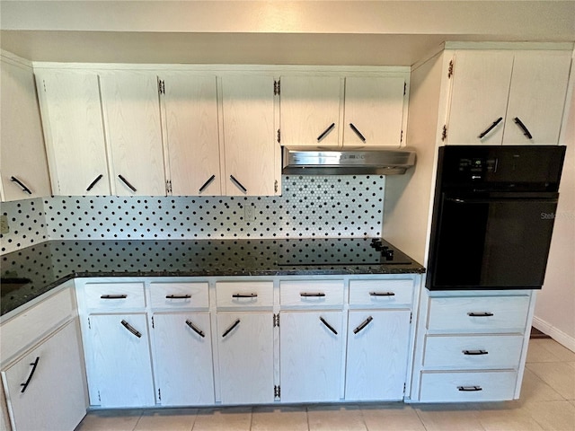 kitchen featuring decorative backsplash, oven, exhaust hood, light tile patterned floors, and white cabinetry