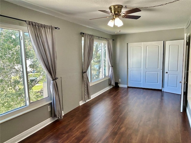 unfurnished bedroom featuring dark wood-type flooring, ceiling fan, and a textured ceiling