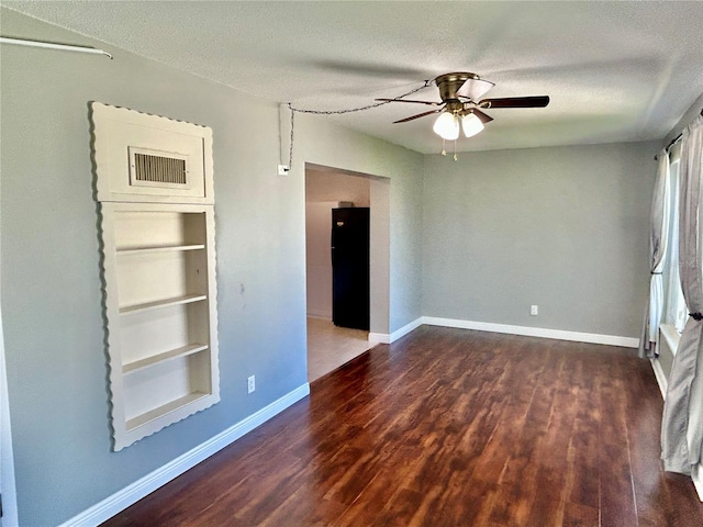 unfurnished room with a textured ceiling, dark wood-type flooring, and ceiling fan