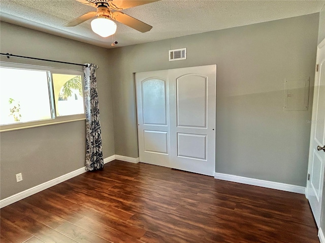 unfurnished bedroom with ceiling fan, a textured ceiling, and dark hardwood / wood-style flooring