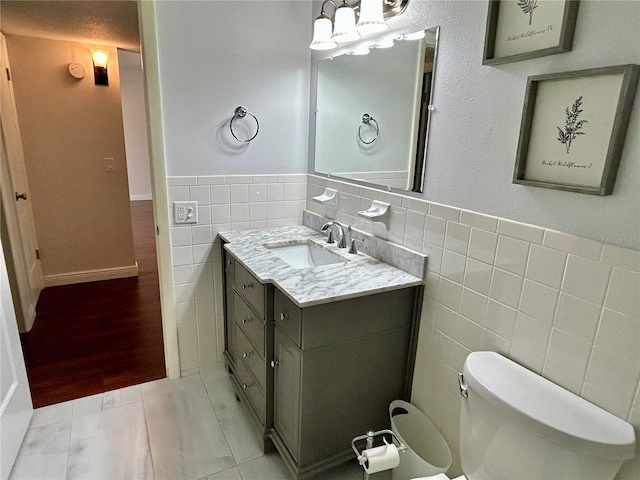 bathroom with tile walls, vanity, hardwood / wood-style flooring, and toilet