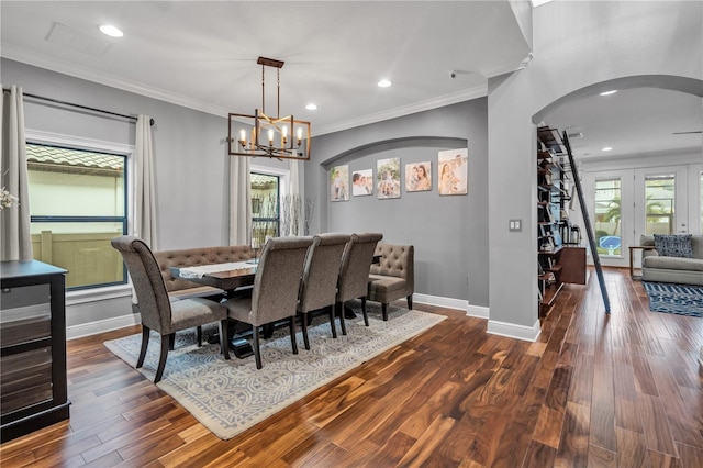 dining area featuring crown molding, a wealth of natural light, dark hardwood / wood-style floors, and a chandelier