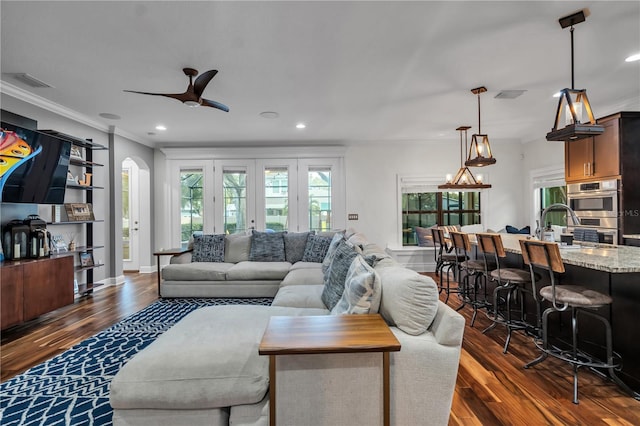 living room with sink, crown molding, dark wood-type flooring, and ceiling fan