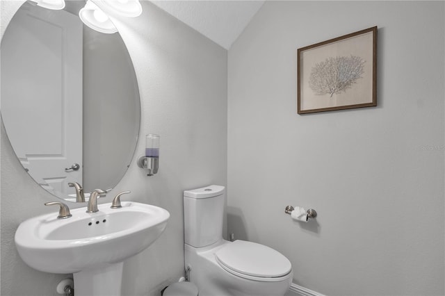 bathroom with sink, toilet, vaulted ceiling, and a textured ceiling