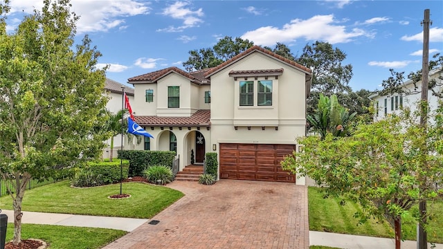 mediterranean / spanish home with a garage and a front lawn