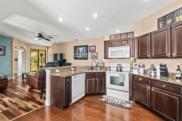 kitchen featuring sink, a textured ceiling, white appliances, and dark hardwood / wood-style flooring