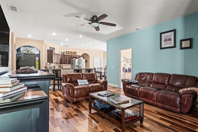 living room featuring light hardwood / wood-style floors, a textured ceiling, and ceiling fan