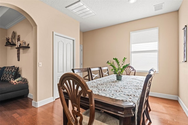 dining area with crown molding, a textured ceiling, and hardwood / wood-style floors