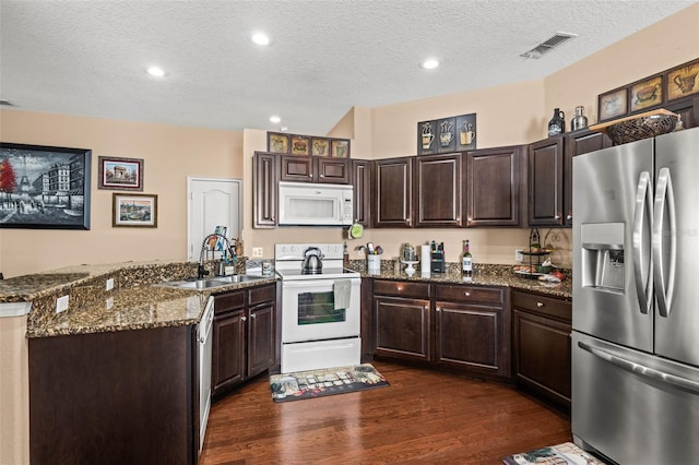 kitchen with sink, dark brown cabinetry, a textured ceiling, white appliances, and dark hardwood / wood-style flooring