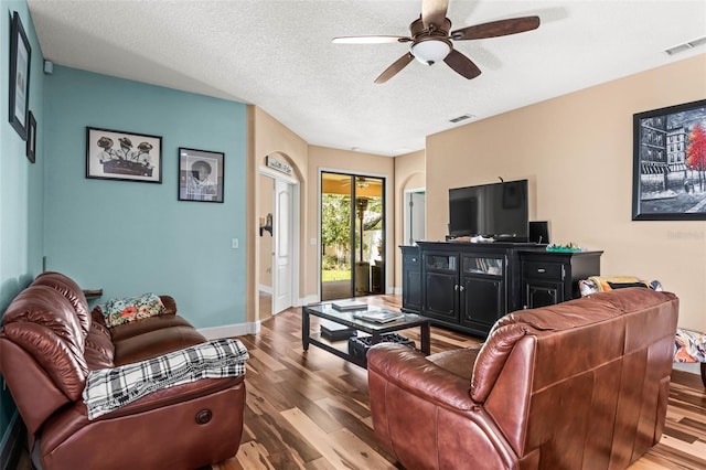 living room with a textured ceiling, hardwood / wood-style flooring, and ceiling fan