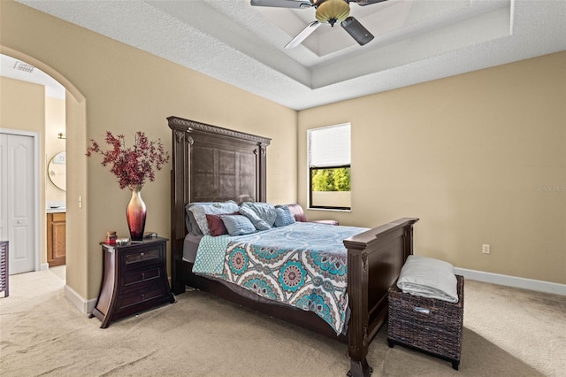 carpeted bedroom featuring connected bathroom, ceiling fan, and a textured ceiling