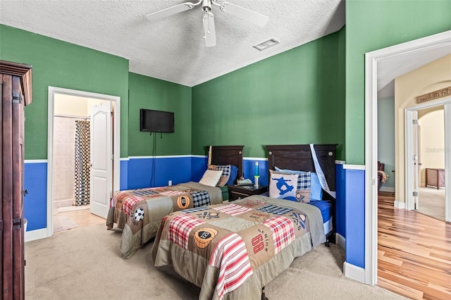 bedroom with connected bathroom, carpet, a textured ceiling, and ceiling fan