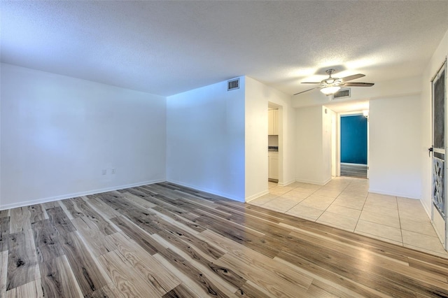 empty room featuring ceiling fan, a textured ceiling, and light wood-type flooring