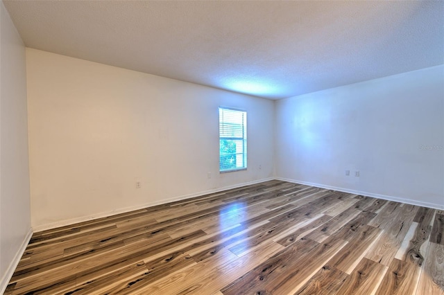 unfurnished room with hardwood / wood-style floors and a textured ceiling