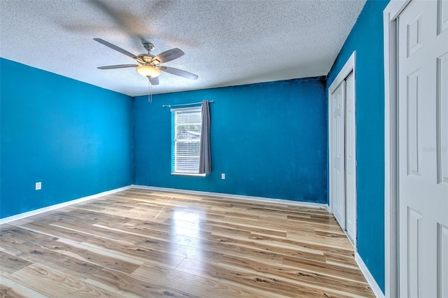 unfurnished bedroom with a textured ceiling, light wood-type flooring, and ceiling fan