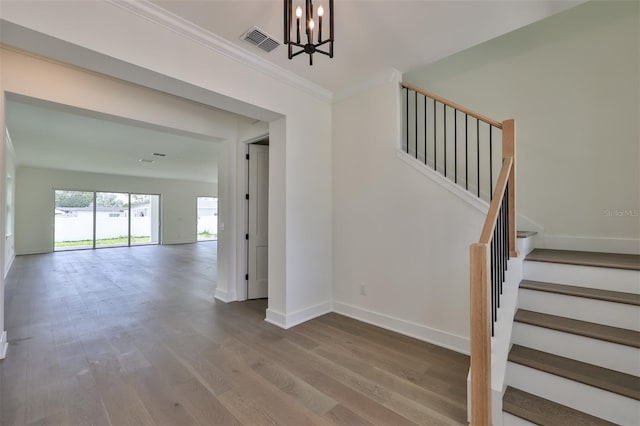 stairs featuring ornamental molding, a chandelier, and hardwood / wood-style floors