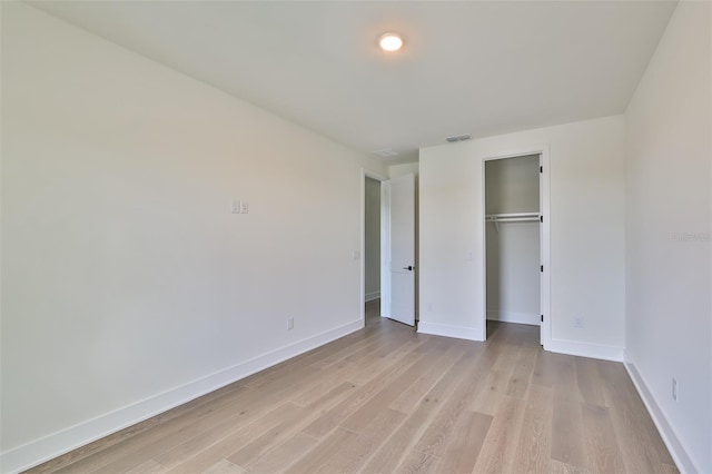 unfurnished bedroom featuring light hardwood / wood-style flooring and a closet