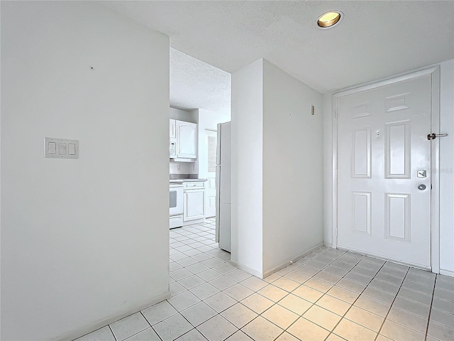 interior space featuring light tile patterned floors, baseboards, and a textured ceiling