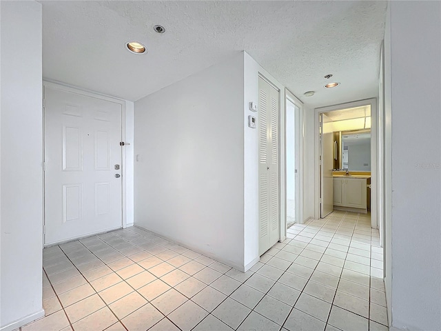 hallway featuring light tile patterned flooring, recessed lighting, and a textured ceiling