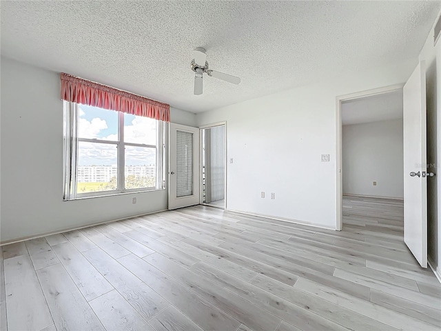 empty room featuring a ceiling fan, light wood-type flooring, and a textured ceiling