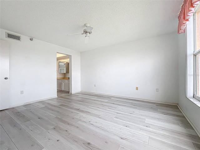 spare room with visible vents, light wood-style floors, a ceiling fan, and a textured ceiling