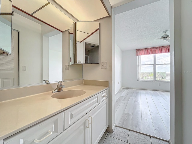 bathroom with vanity, wood finished floors, a ceiling fan, and a textured ceiling