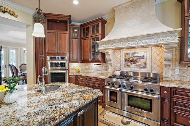 kitchen with pendant lighting, light stone countertops, appliances with stainless steel finishes, and backsplash