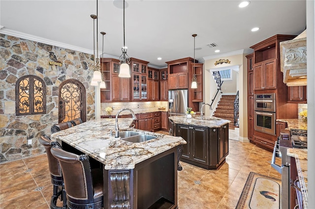 kitchen with tasteful backsplash, an island with sink, appliances with stainless steel finishes, sink, and decorative light fixtures