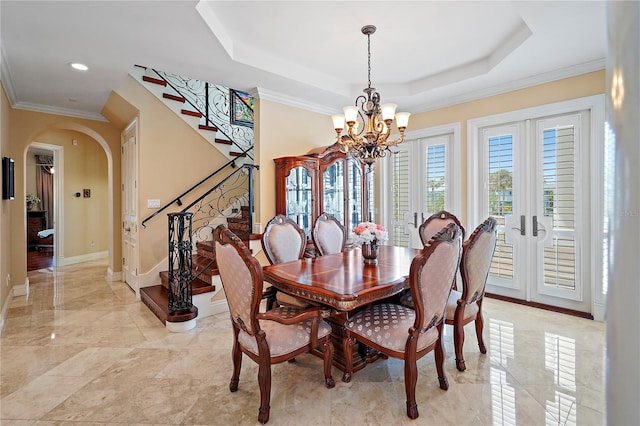 dining space featuring ornamental molding, french doors, a tray ceiling, and an inviting chandelier