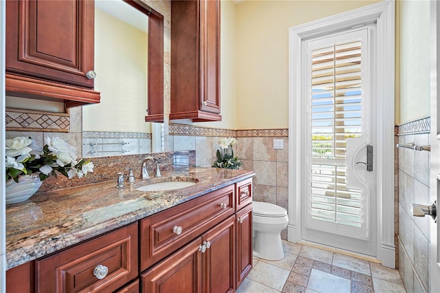 bathroom featuring toilet, vanity, and tile walls