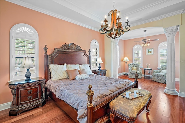 bedroom with hardwood / wood-style floors, decorative columns, crown molding, and a chandelier