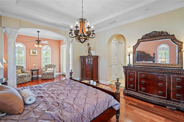 bedroom featuring multiple windows, wood-type flooring, crown molding, and decorative columns