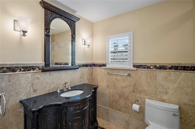 bathroom with toilet, vanity, and tile walls