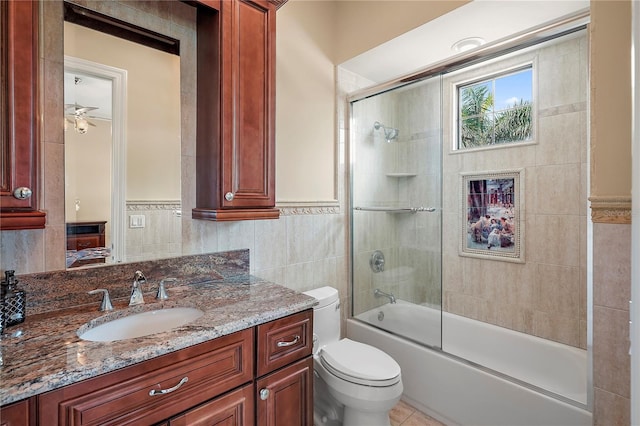 full bathroom featuring vanity, tile walls, bath / shower combo with glass door, and toilet