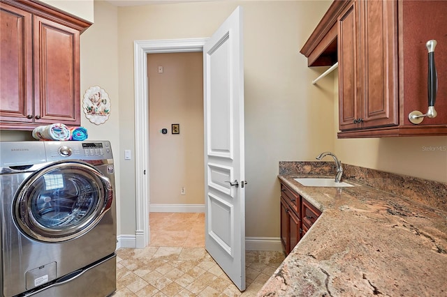 clothes washing area featuring washer / dryer, light tile patterned flooring, sink, and cabinets