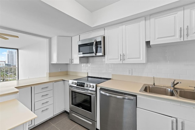 kitchen with tasteful backsplash, dark tile patterned flooring, sink, stainless steel appliances, and white cabinets