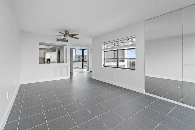 unfurnished living room with ceiling fan and dark tile patterned flooring